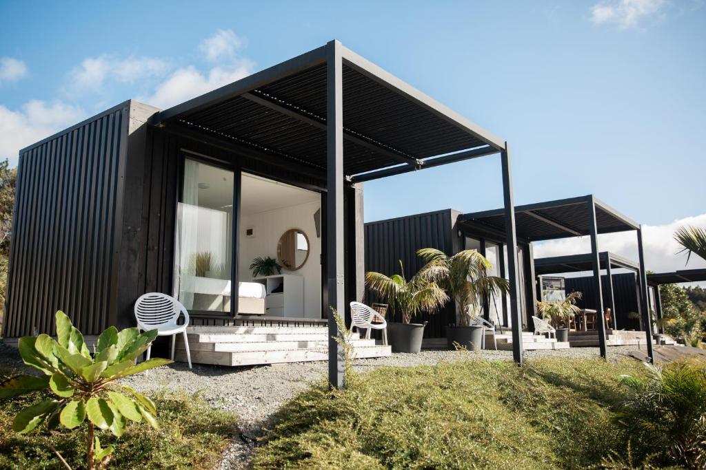 a black house with a black roof at Aotearoa Surf Eco Pods in Te Arai