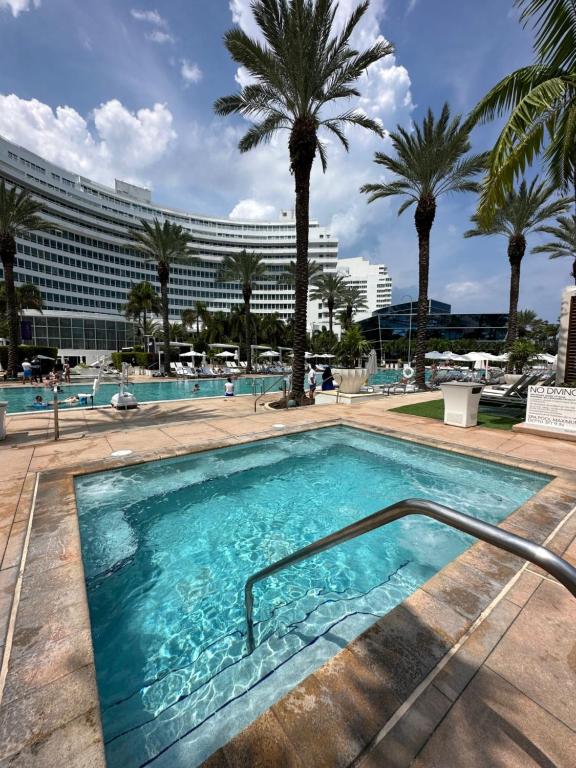 een zwembad met palmbomen en een gebouw bij Fontainebleau Miami Beach,Tresor in Miami Beach