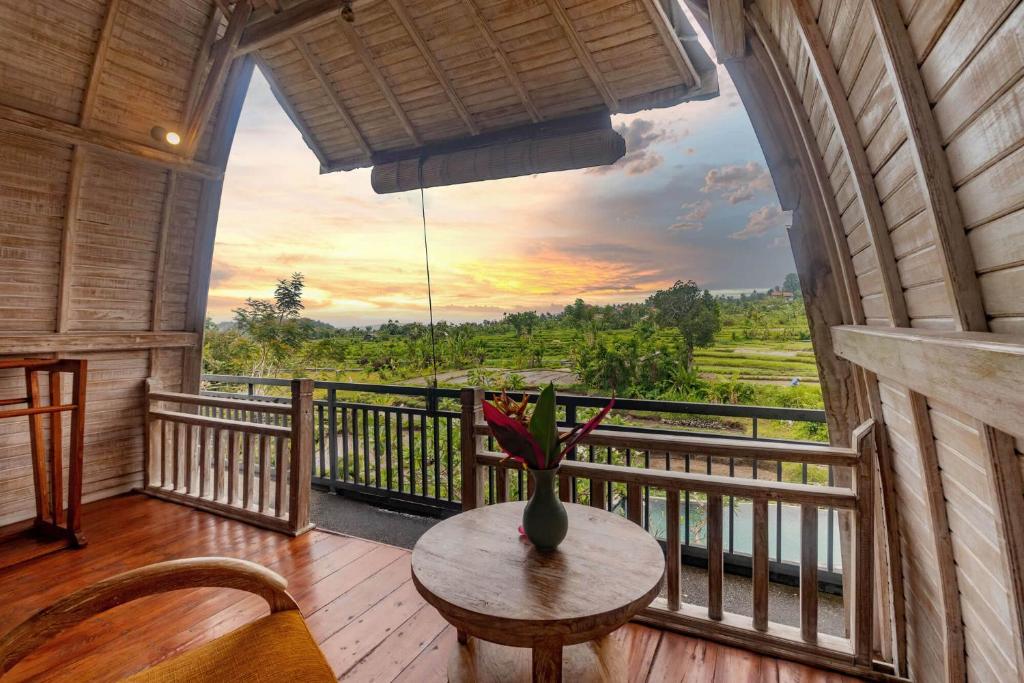 Habitación con mesa y balcón con vistas. en AlamGangga Villas Tirta Gangga, en Tirtagangga