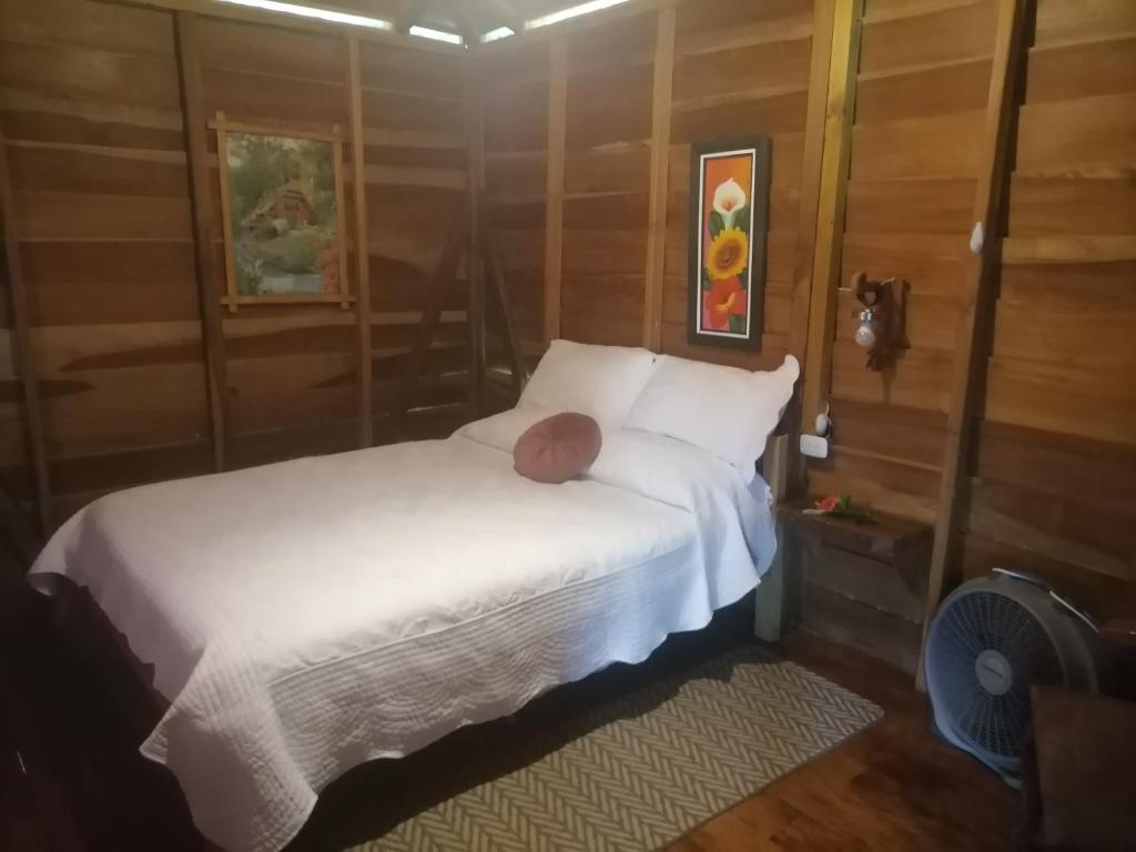 a bedroom with a white bed with a stuffed animal on it at Rancho de Moncho in Bijagua