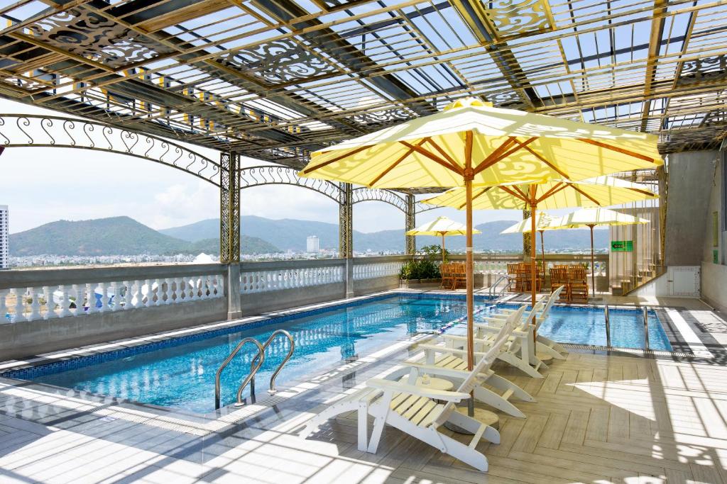 einen Pool mit Stühlen und Sonnenschirmen auf einem Gebäude in der Unterkunft Pearl Beach Hotel Quy Nhon in Quy Nhon