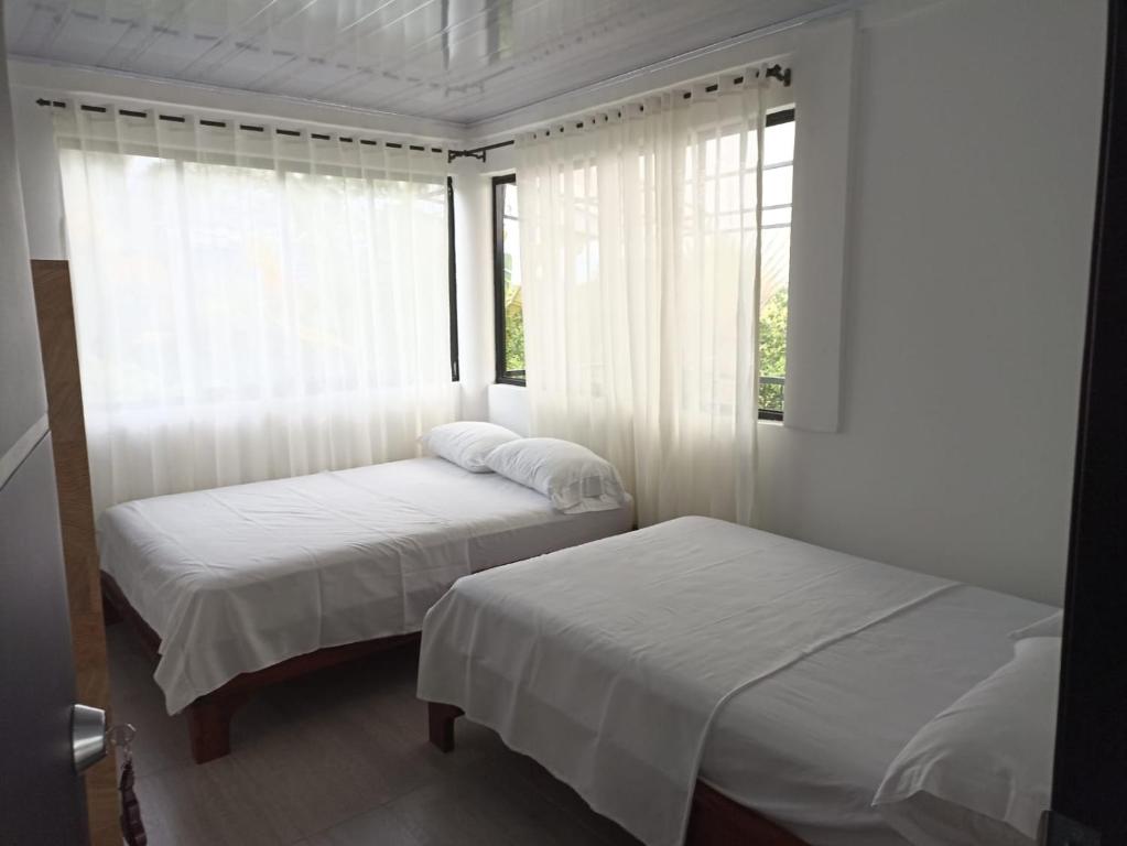 2 camas en una habitación con ventana en HOTEL EL RUBY, en San Martín