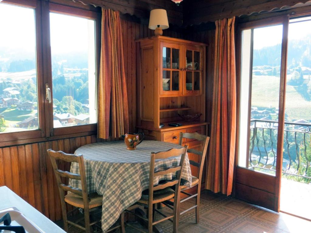 ein Esszimmer mit einem Tisch, Stühlen und Fenstern in der Unterkunft Appartement Les Gets, 2 pièces, 4 personnes - FR-1-671-227 in Les Gets