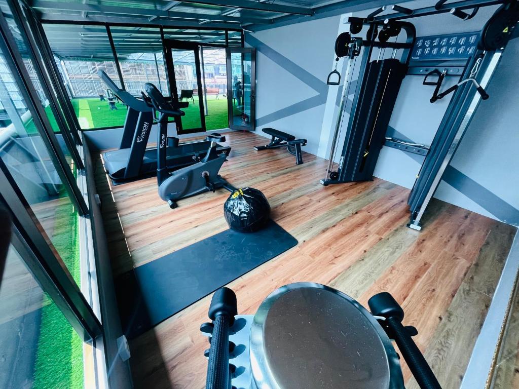 A glass-fronted gym with cardio equipment, a cable machine, bench and free weights.