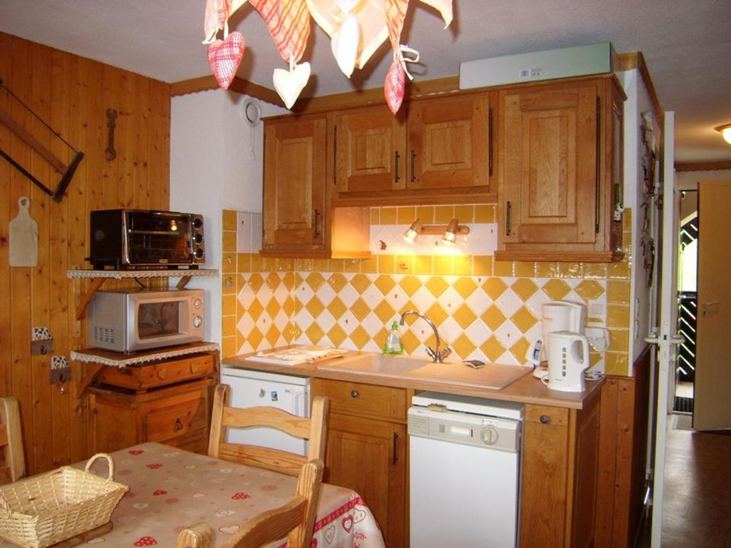a kitchen with wooden cabinets and a sink and a table at Appartement cosy avec Wifi, 4 pers, 300m des pistes à Crest-Voland - FR-1-733-141 in Crest-Voland