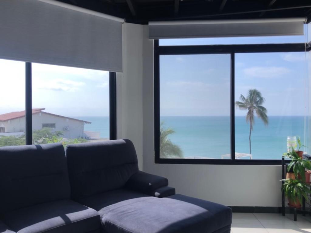a living room with a couch and large windows at Apartamento en excelente ubicación in Manta