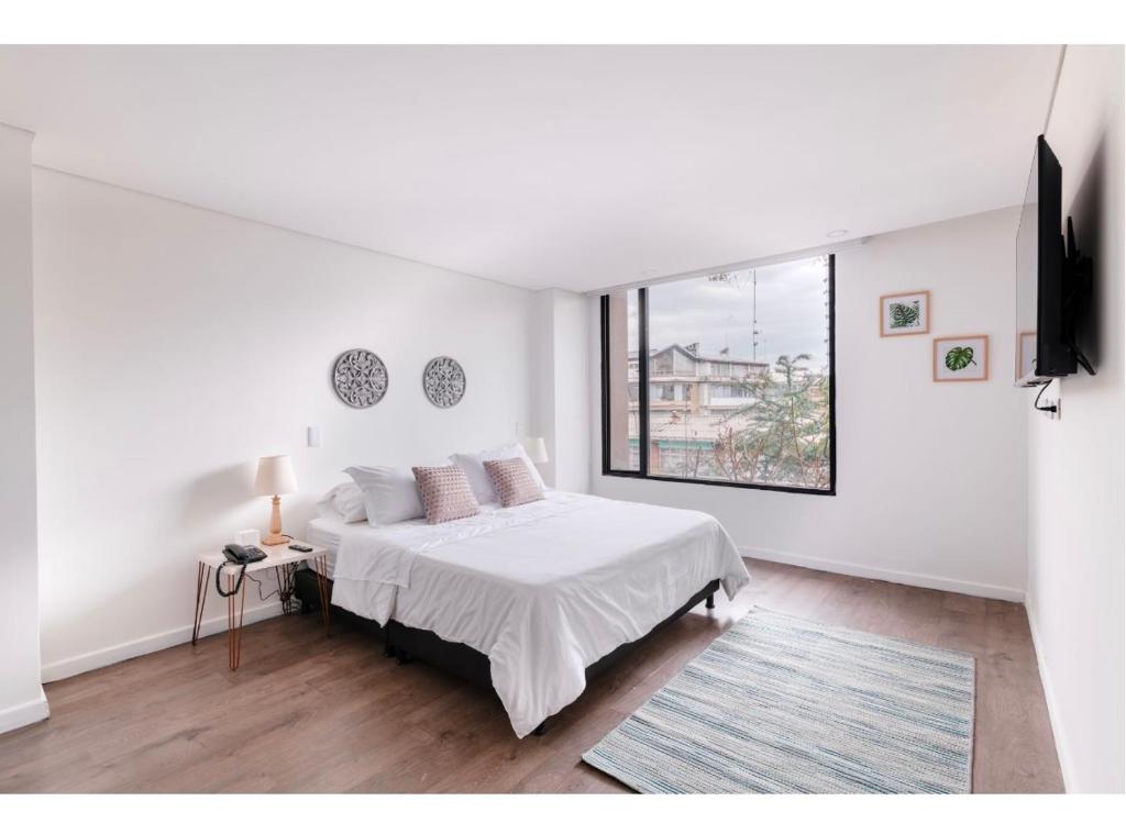 Habitación blanca con cama y ventana en Acogedor apartamento!, en Bogotá