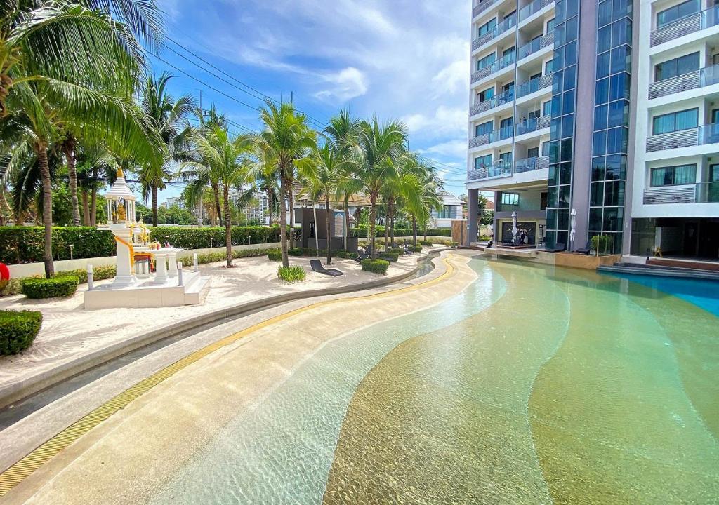 a swimming pool in front of a building with palm trees at Laguna Beach Resort 1 Condominium in Jomtien Beach