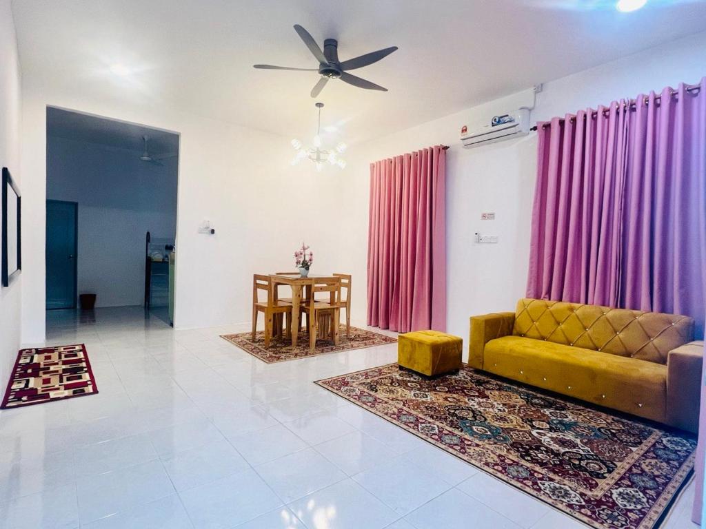 Hayyan Homestay Kuala Lipis في كوالا ليبيس: غرفة معيشة مع أريكة صفراء وطاولة