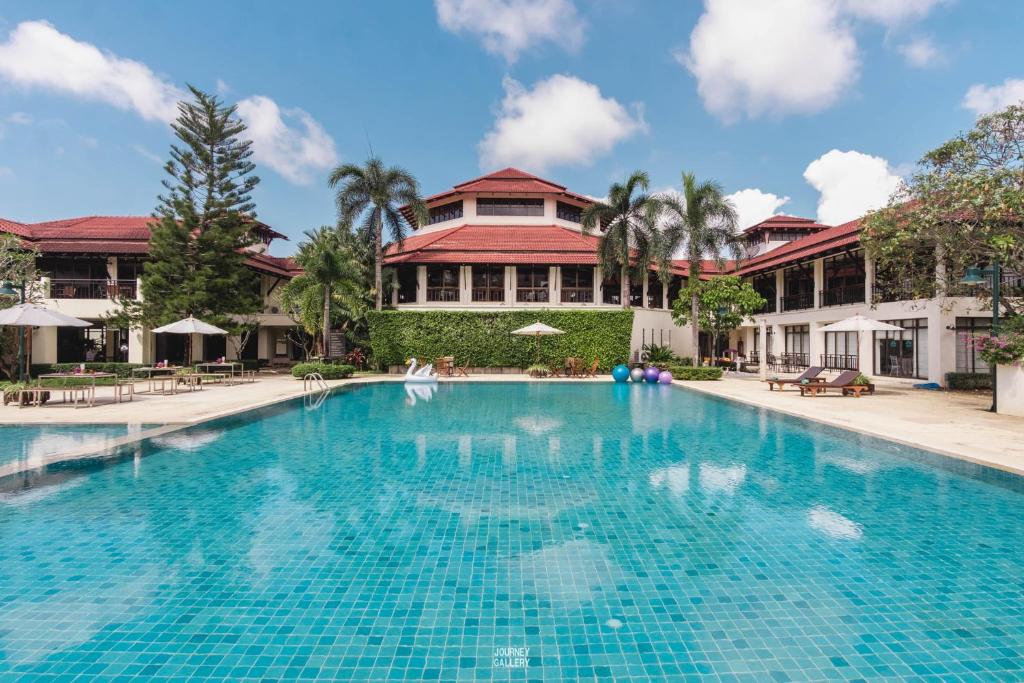 une grande piscine en face d'un bâtiment dans l'établissement Maneechan Resort - SHA Extra Plus, à Chanthaburi