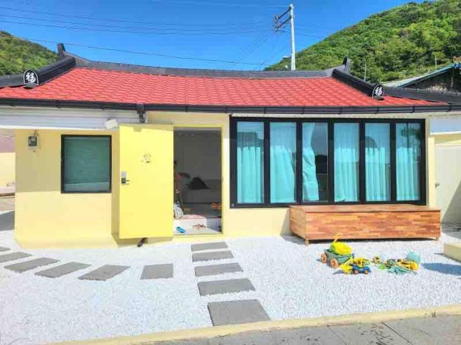 una pequeña casa amarilla con techo rojo en Onheim en Tongyeong