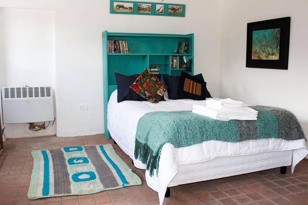 a bedroom with a bed with a green headboard at Las Glicinas de Chacras in Chacras de Coria