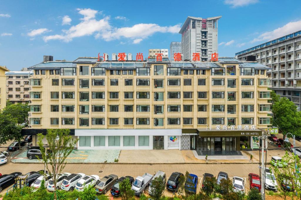een groot gebouw met auto's geparkeerd op een parkeerplaats bij Yiwu Baide Theme Hotel in Yiwu