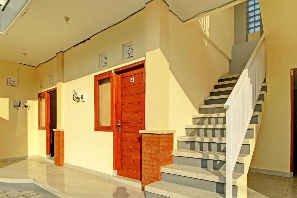 eine Treppe in einem Haus mit einer Holztür in der Unterkunft OYO 92952 Nirmala Guest House in Singaraja