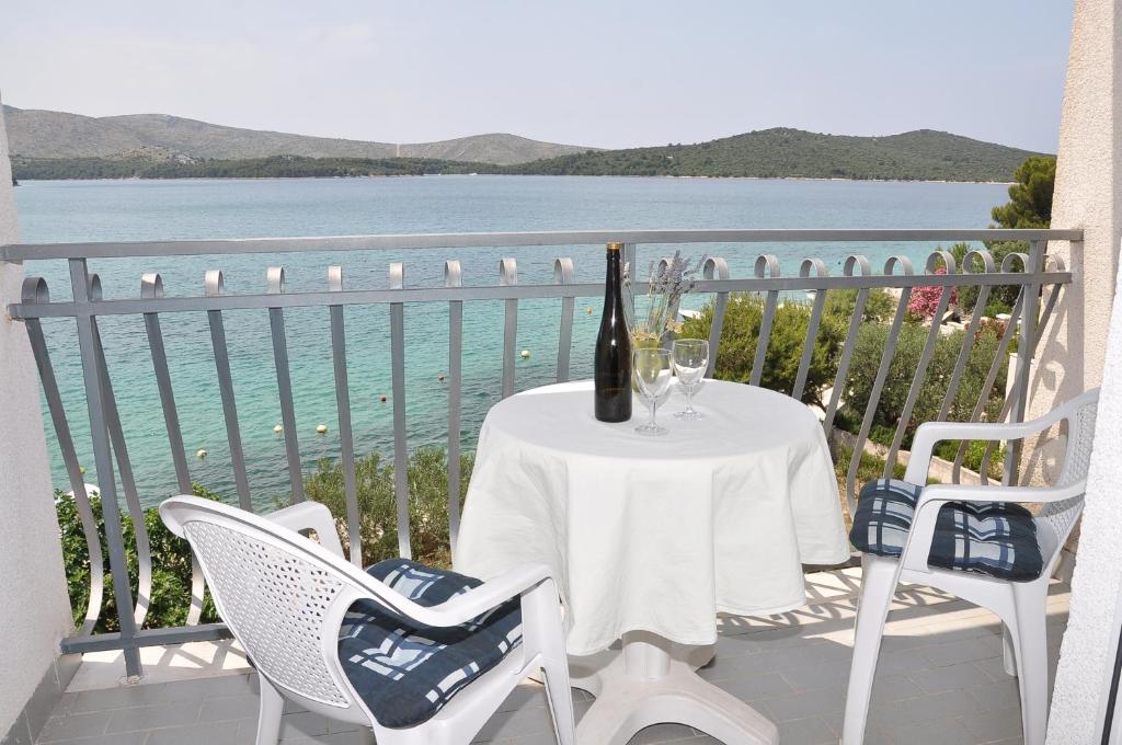 a table with a bottle of wine and chairs on a balcony at Apartments Pralija Mile in Zaboric