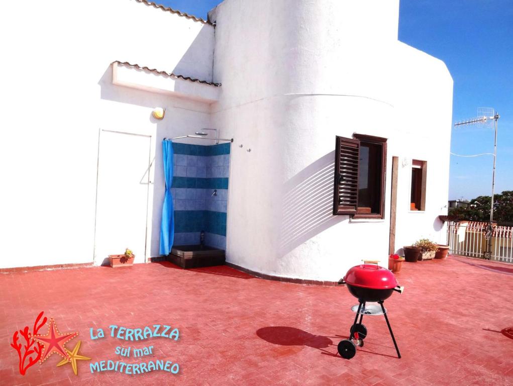 un piccolo edificio bianco con un pavimento rosso accanto di La Terrazza Sul Mar Mediterraneo a Marinella di Selinunte