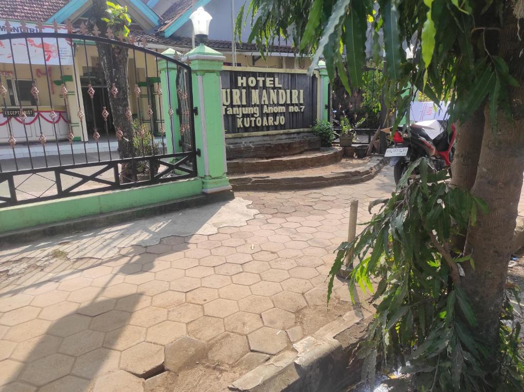 OYO 93048 Hotel Puri Mandiri في Purworejo: مبنى امام شارع فيه شجرة