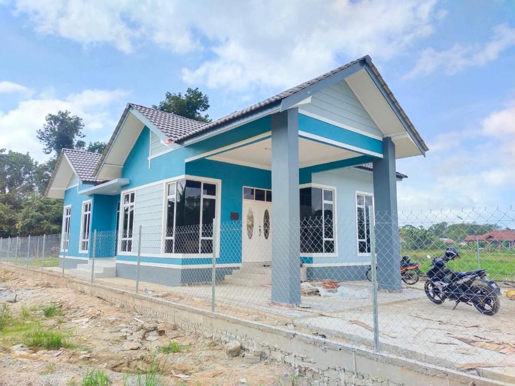 a blue house with a motorcycle parked in front of it at Homestay Dena Moon Inn in Tumpat