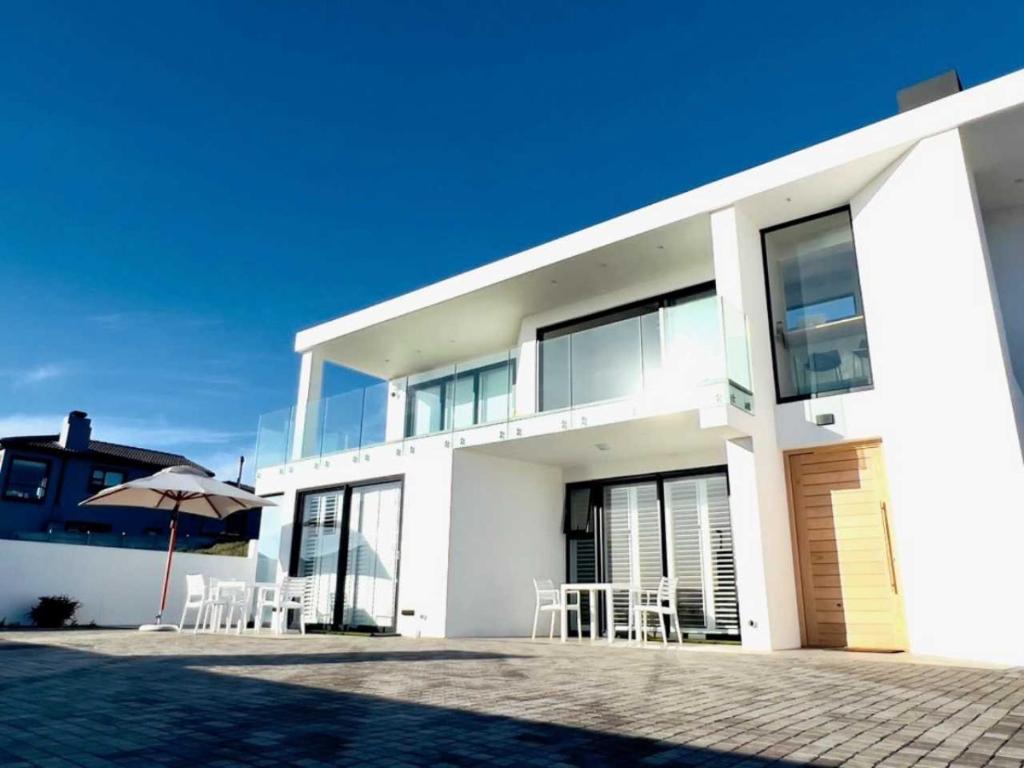 Casa blanca con sillas y sombrilla en Flip Flops Villa two rooms, en Yzerfontein