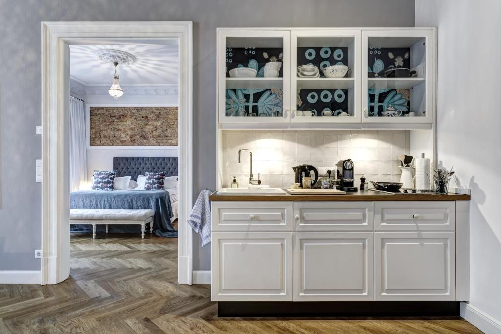 a kitchen with white cabinets and a room with a bed at Gorki Apartments in Berlin