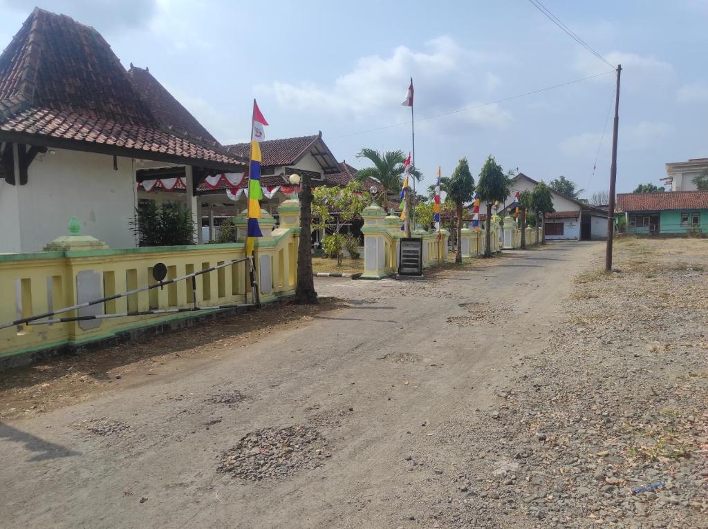 a dirt road with a yellow fence next to a street at Capital O 93024 Hotel Ganesha in Purworejo