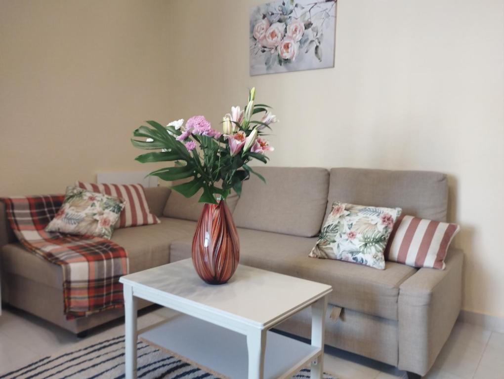 a living room with a couch and a vase of flowers on a table at Spacious apartment La Mata pool&beach in Torrevieja