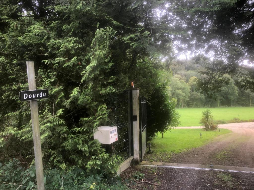 a street sign next to a tree with a fence at Gite équestre du Dourdu in Lopérec