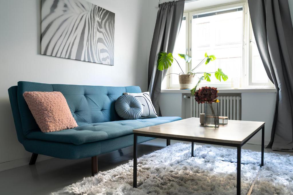 a blue couch in a living room with a table at Stylish Studio at the Heart of Helsinki in Helsinki