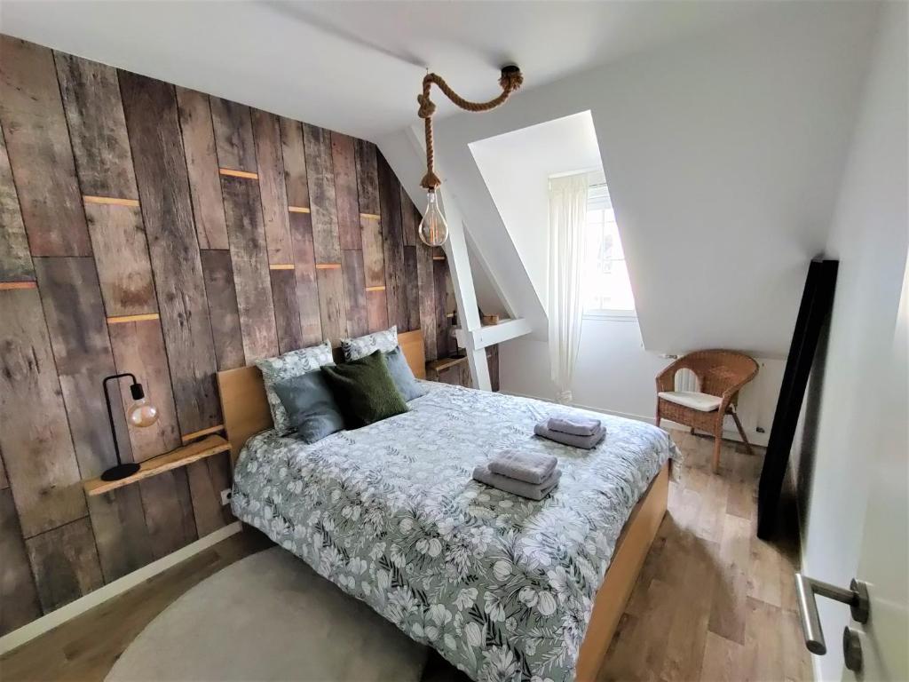 a bedroom with a bed and a wooden wall at Appartement NATURA 2 chambres in Vitré