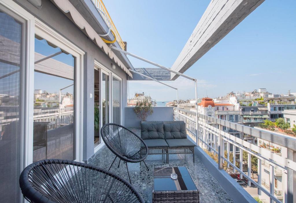 a balcony with two chairs and a couch at Daphne by halu! : Downtown family penthouse in Thessaloniki