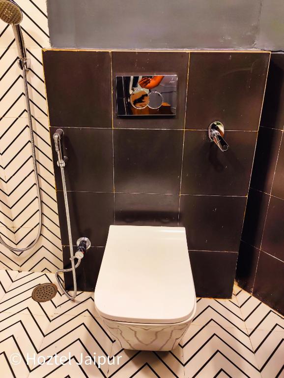 a bathroom with a toilet and a black wall at Hoztel Jaipur in Jaipur