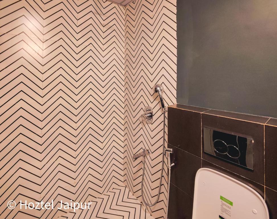 a bathroom with a checkered wall with a urinal at Hoztel Jaipur in Jaipur
