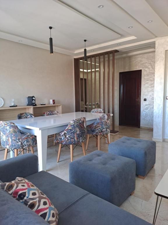 un soggiorno con tavolo e sedie bianchi di vacance et confort les sablettes a Mohammedia
