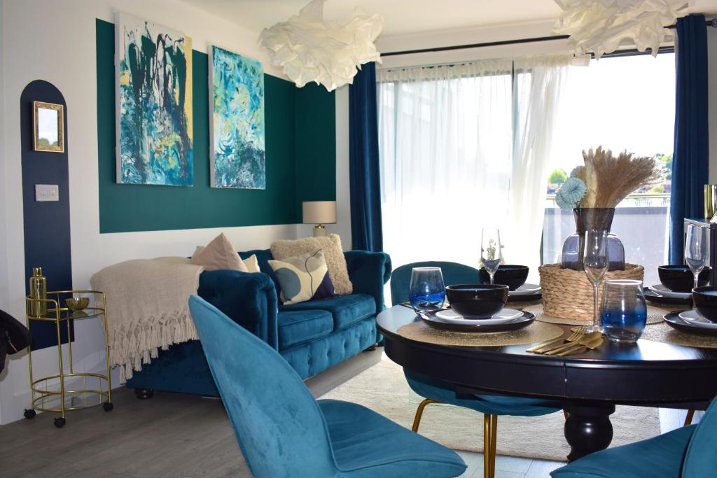 ein Wohnzimmer mit einem blauen Sofa und einem Tisch in der Unterkunft R V Properties Luxury Suites 21 & 23 in Hemel Hempstead