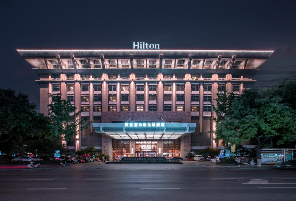 un edificio iluminado con un cartel de hilton por la noche en Hilton Xi&#39;an, en Xi&#39;an