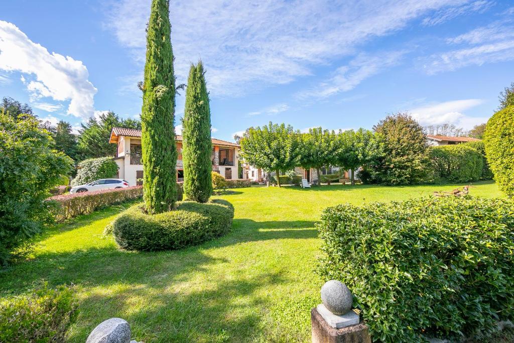 einen Hof mit Zypressen und einem Haus in der Unterkunft Timeless l' Antico Mulino Della Bozza - Happy Rentals in Brebbia