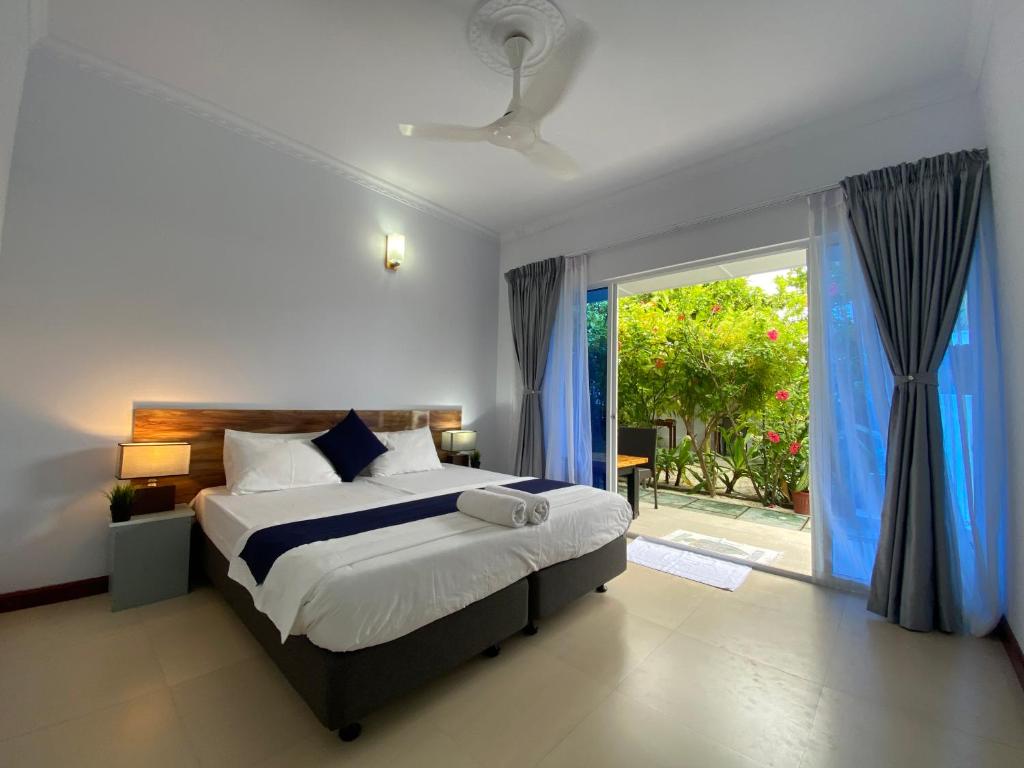 1 dormitorio con 1 cama y puerta corredera de cristal en Tides Dhigurah en Dhigurah