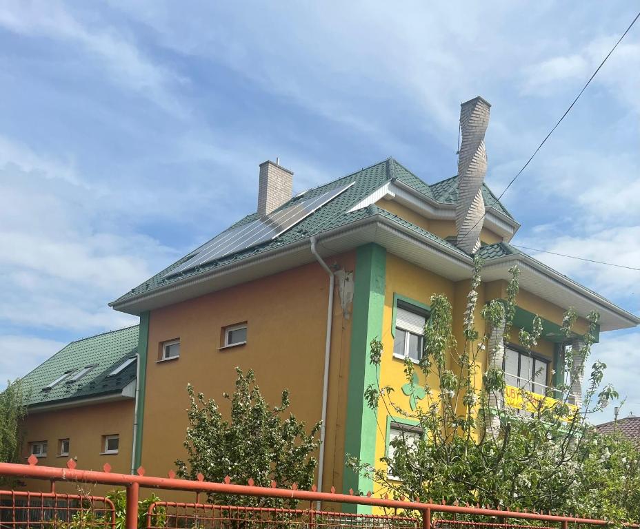 a yellow and green house with a roof at LACNÉ UBYTOVANIE GABČÍKOVO in Gabčíkovo