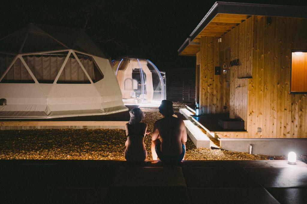 dots by Dot Glamping Suite 001 في فوجيكاواجوتشيكو: a man and a woman standing in front of a rv