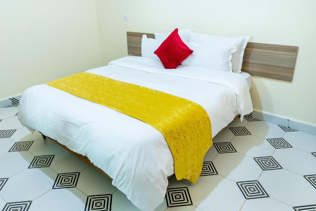a bedroom with a white bed with a yellow and red blanket at Mang City Hotel in Nairobi