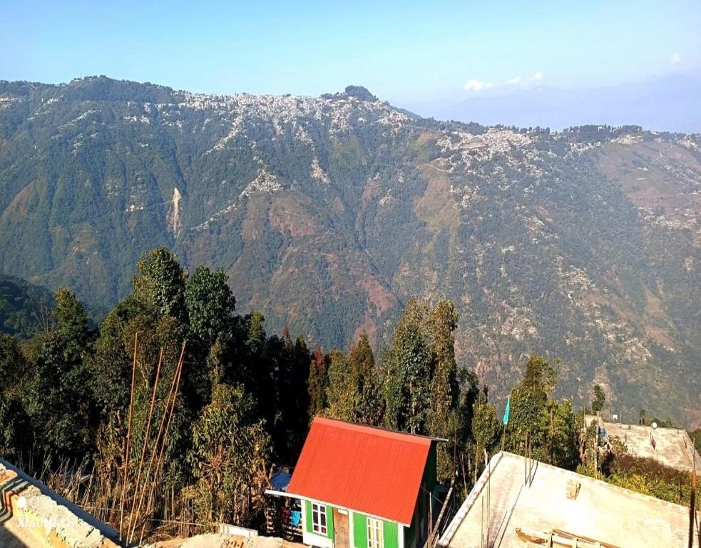 uma casa com um telhado vermelho em frente a uma montanha em Rinchen Ghising Homestay by StayApart em Ghum
