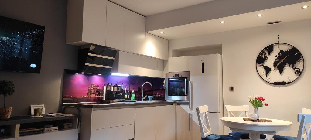 a kitchen with white cabinets and a table and a clock at Ozzy Cozy in Zagreb