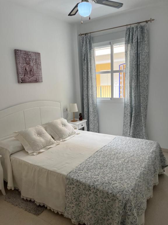 Un dormitorio con una cama blanca con una ventana. en Apartamento Plata Real, en Sanlúcar de Barrameda