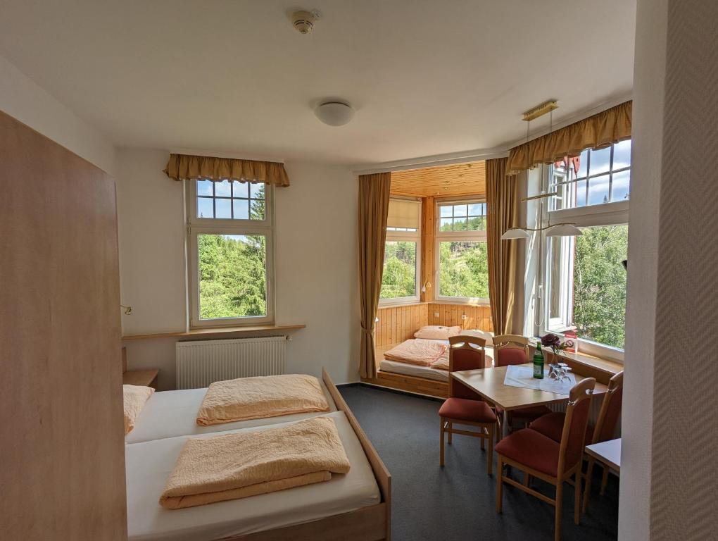 a hotel room with two beds and a table at Waldgasthaus & Berghotel Steinerne Renne in Wernigerode