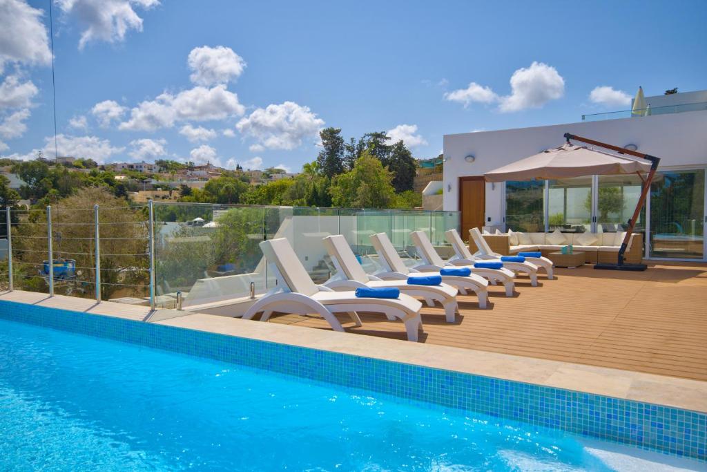 uma piscina com espreguiçadeiras e uma piscina em Villa Goa - By Luxury Villas Malta em Mellieħa