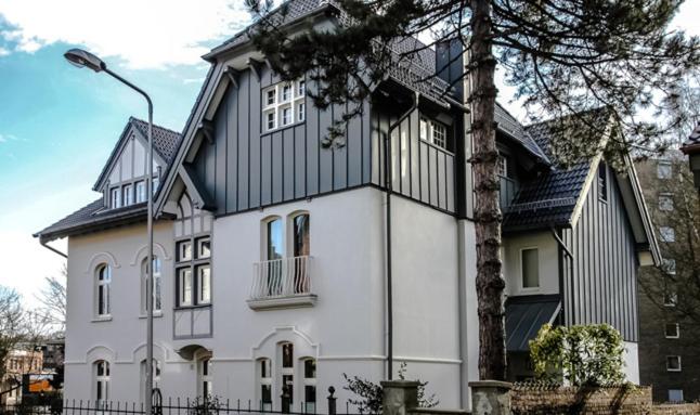 uma grande casa branca com um telhado preto em Fabrikantenvilla em Erkrath