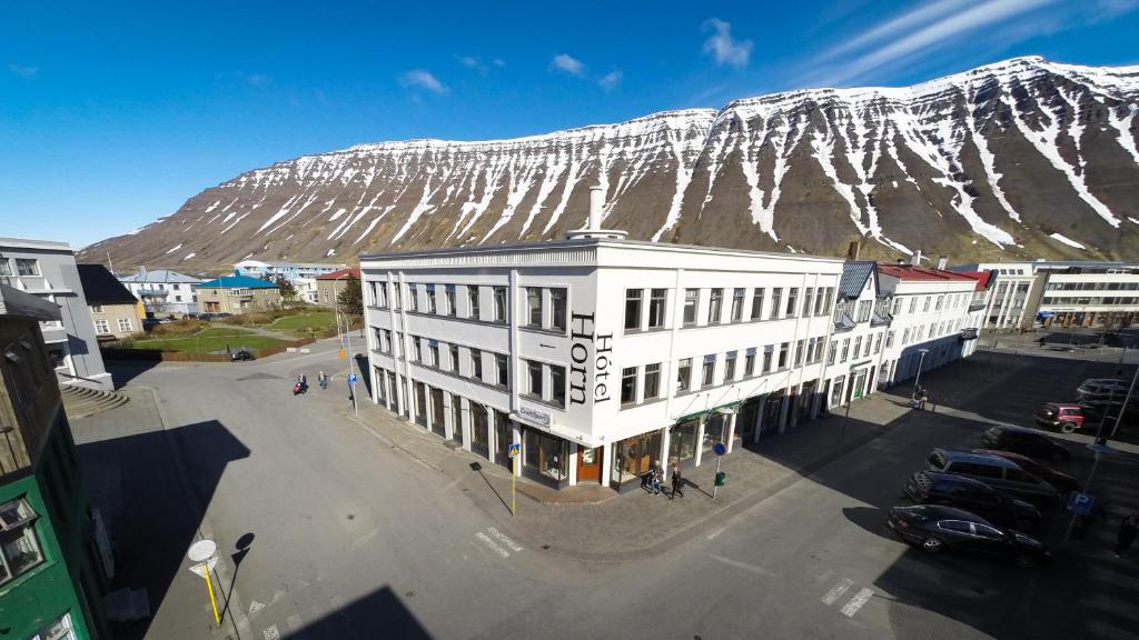 a white building with a snow covered mountain in the background at Hotel Isafjordur - Horn in Ísafjörður