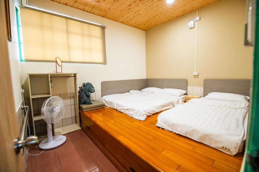 two beds in a room with a fan at 家暖暖,老屋新生,房源內有戶外空間,嘉義市民宿013號 in Chiayi City
