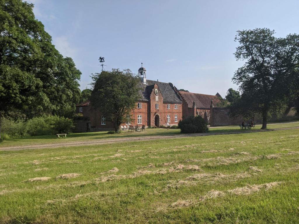 une ancienne maison en briques rouges avec un champ devant elle dans l'établissement Spixworth Hall Cottages, à Spixworth