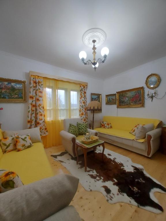 a living room with a yellow couch and a table at Vikendica Nada in Ljubovija